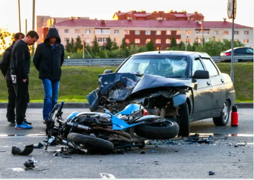 People looking over a bad accident between a car and a motorcycle.