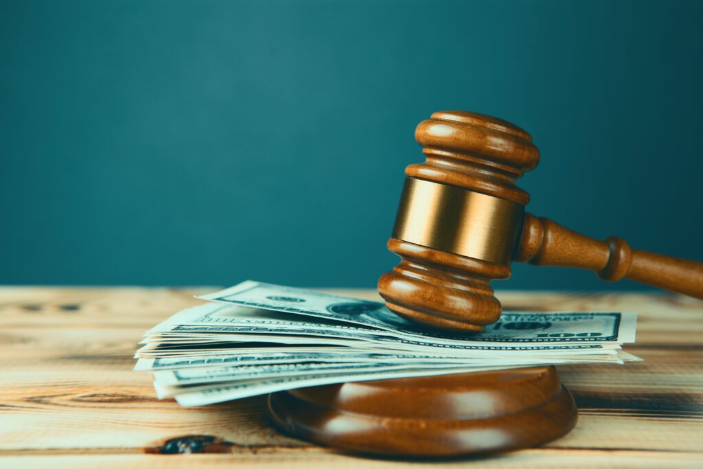 A gavel with a stack of money underneath it.