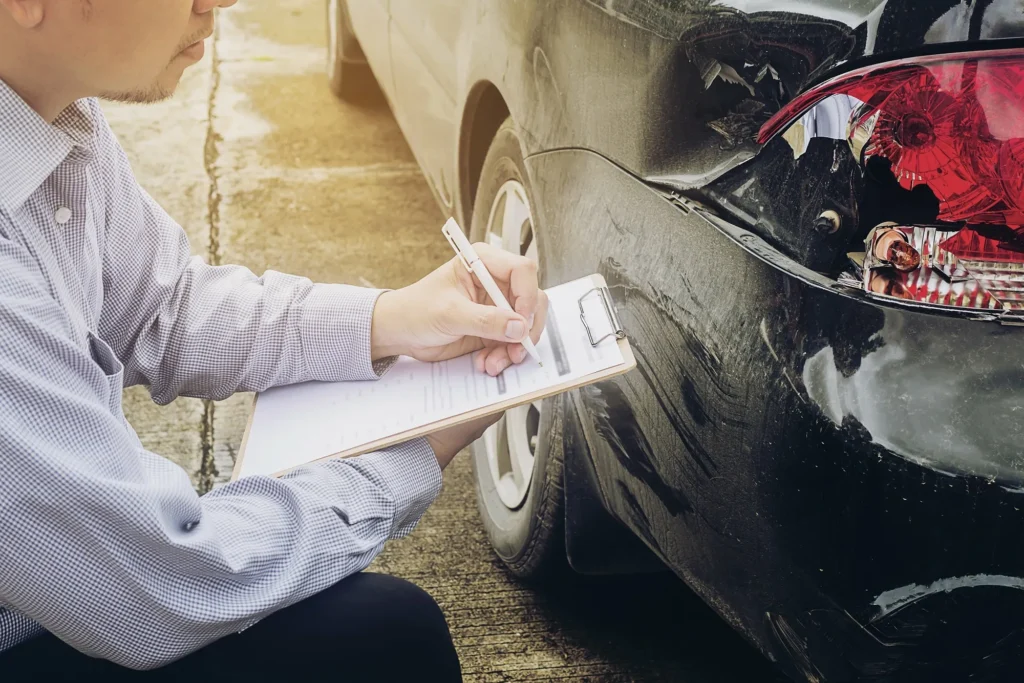 A person documenting the damage to a car.