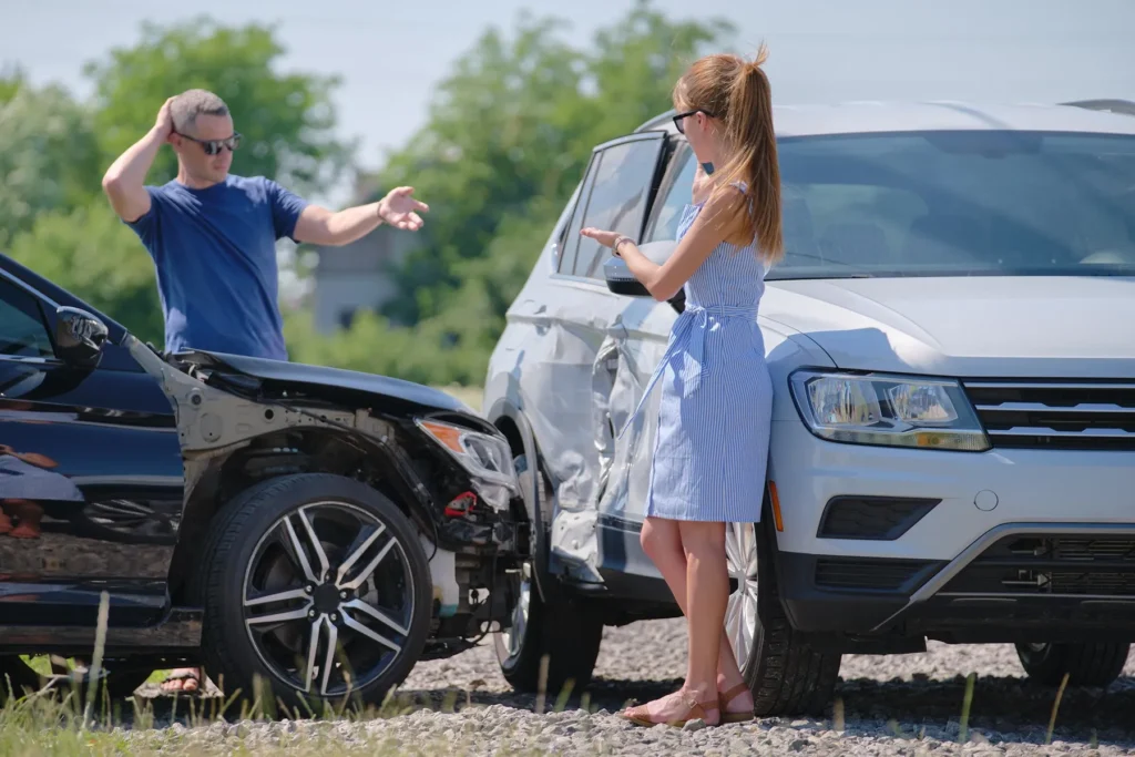 Two people outside their vehicles after getting into a car accident.
