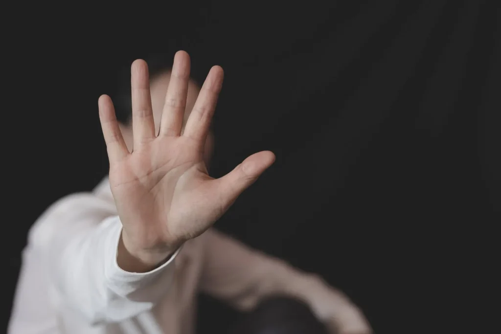 A person holding their hand up in fear.