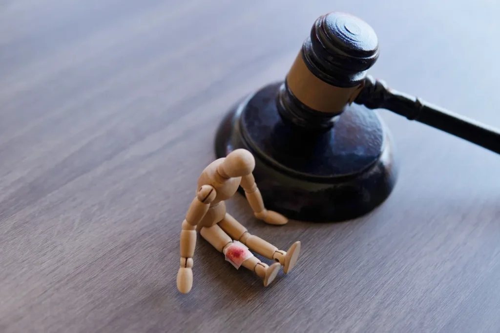 A wooden doll with a bloody bandage and a gavel placed on a table.