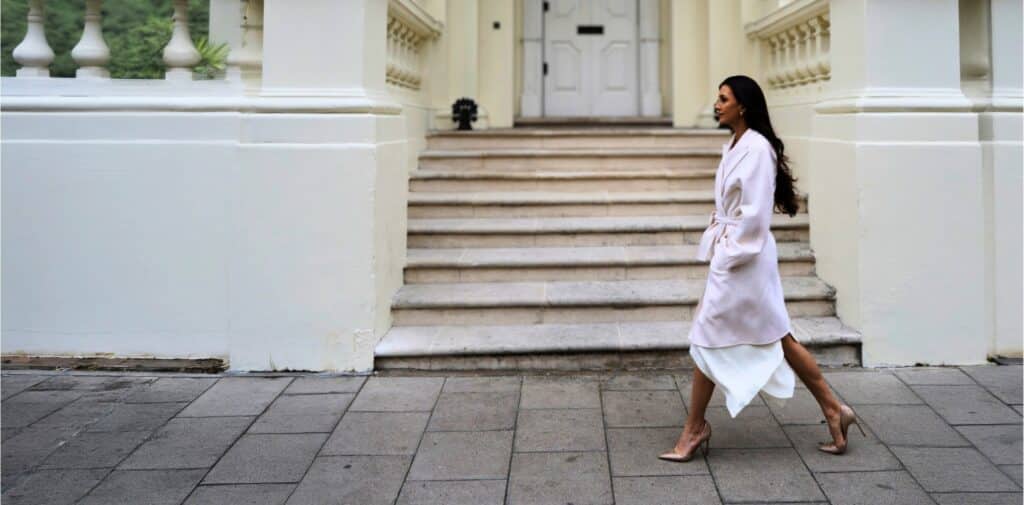Aimée Robert walking toward the entrance of a building, in motion, not looking at the camera