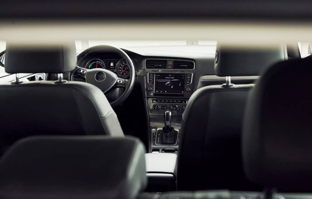 An empty driver's seat and steering wheel seen from the rear of a car interior