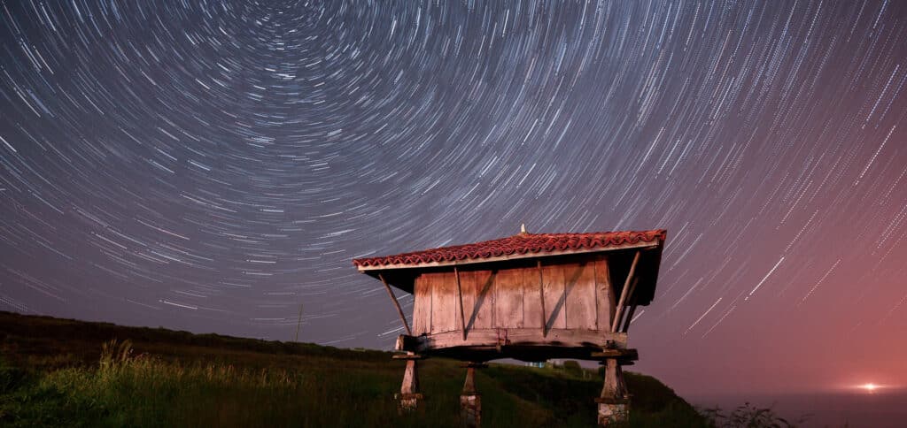Circular star trails wheeling above the roof of an isolated building at night