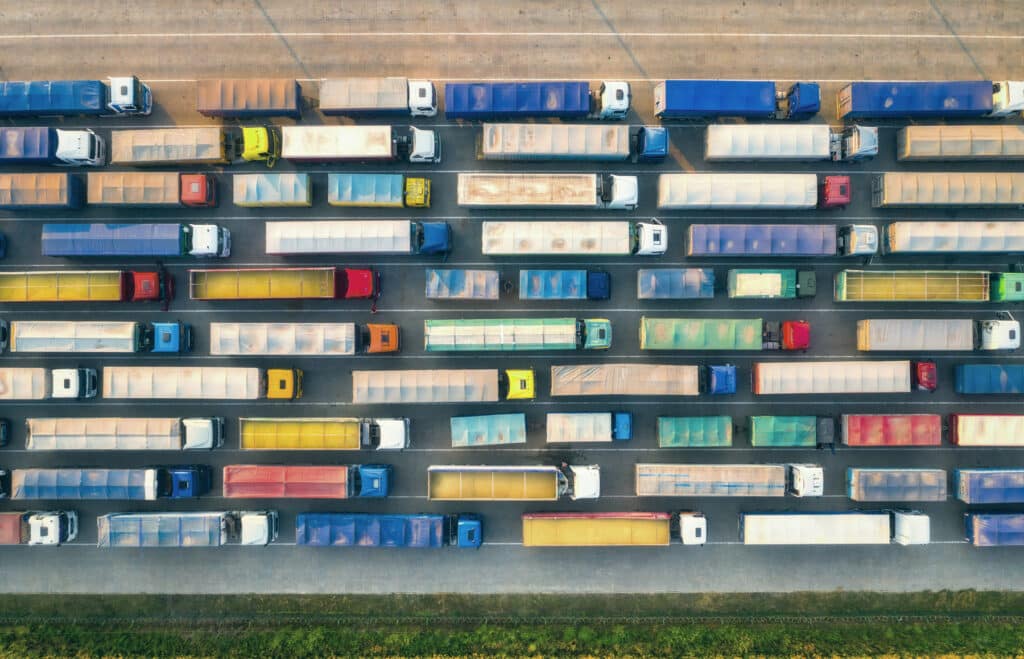 An overhead view of tractor-trailers parked in rows across a freight terminal
