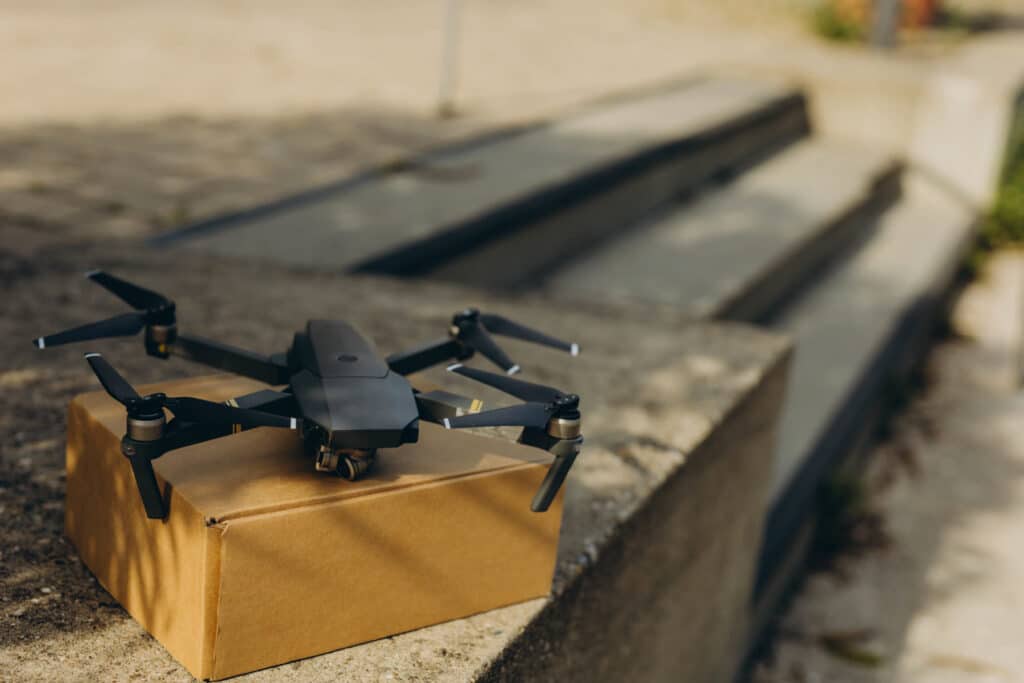 A delivery drone resting on a cardboard package on a concrete staircase