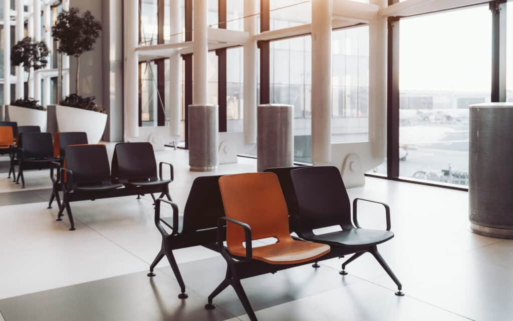 Rows of empty chairs in a bright, glass-walled waiting area