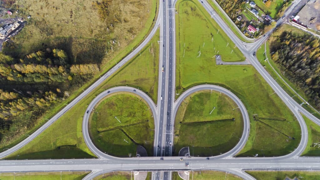 Aerial view of a highway interchange with two ramps curving apart through green fields