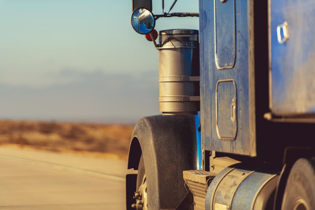 The front wheel and fender of a semi truck parked on a desert highway