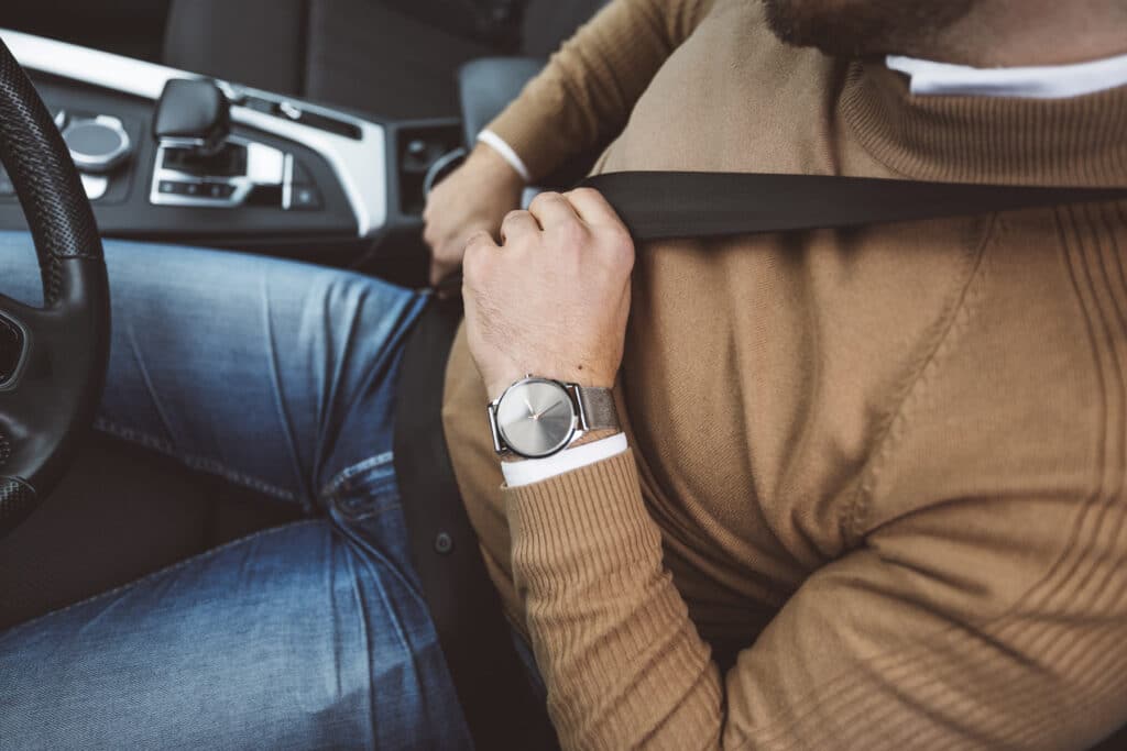 Close view of hands pulling a seatbelt across the body while seated in a car